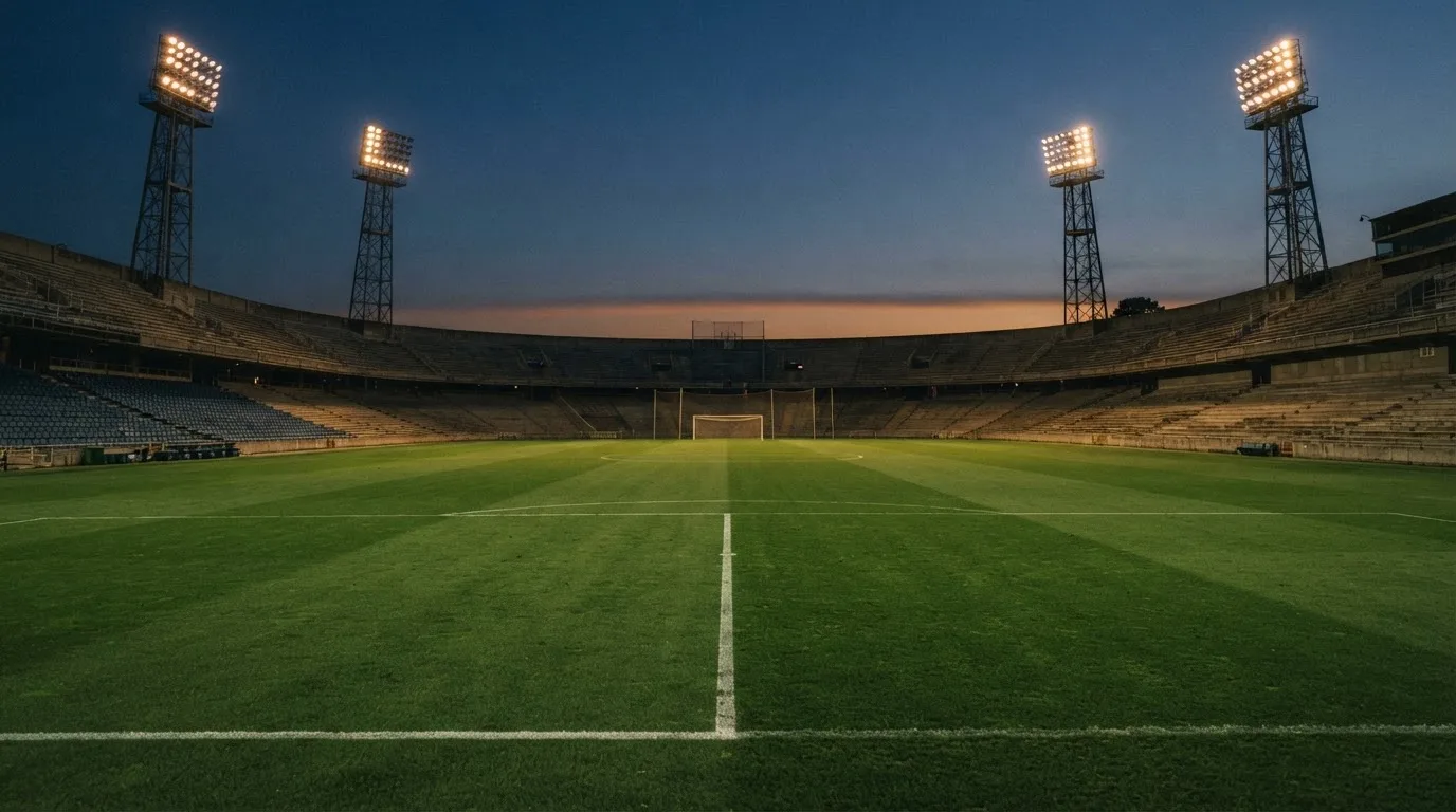 Een leeg voetbalstadion met lichtmasten bij schemering