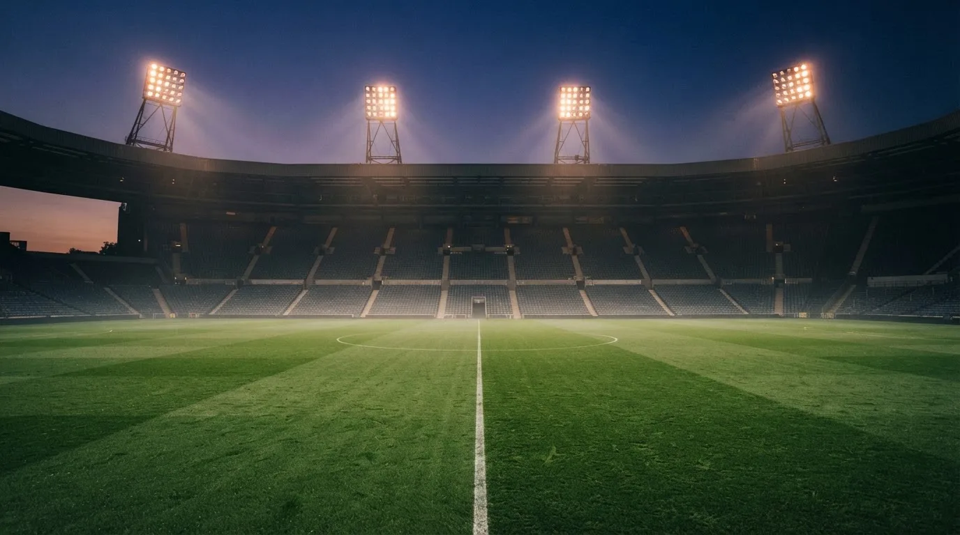 Een leeg voetbalstadion met lichtmasten bij schemering