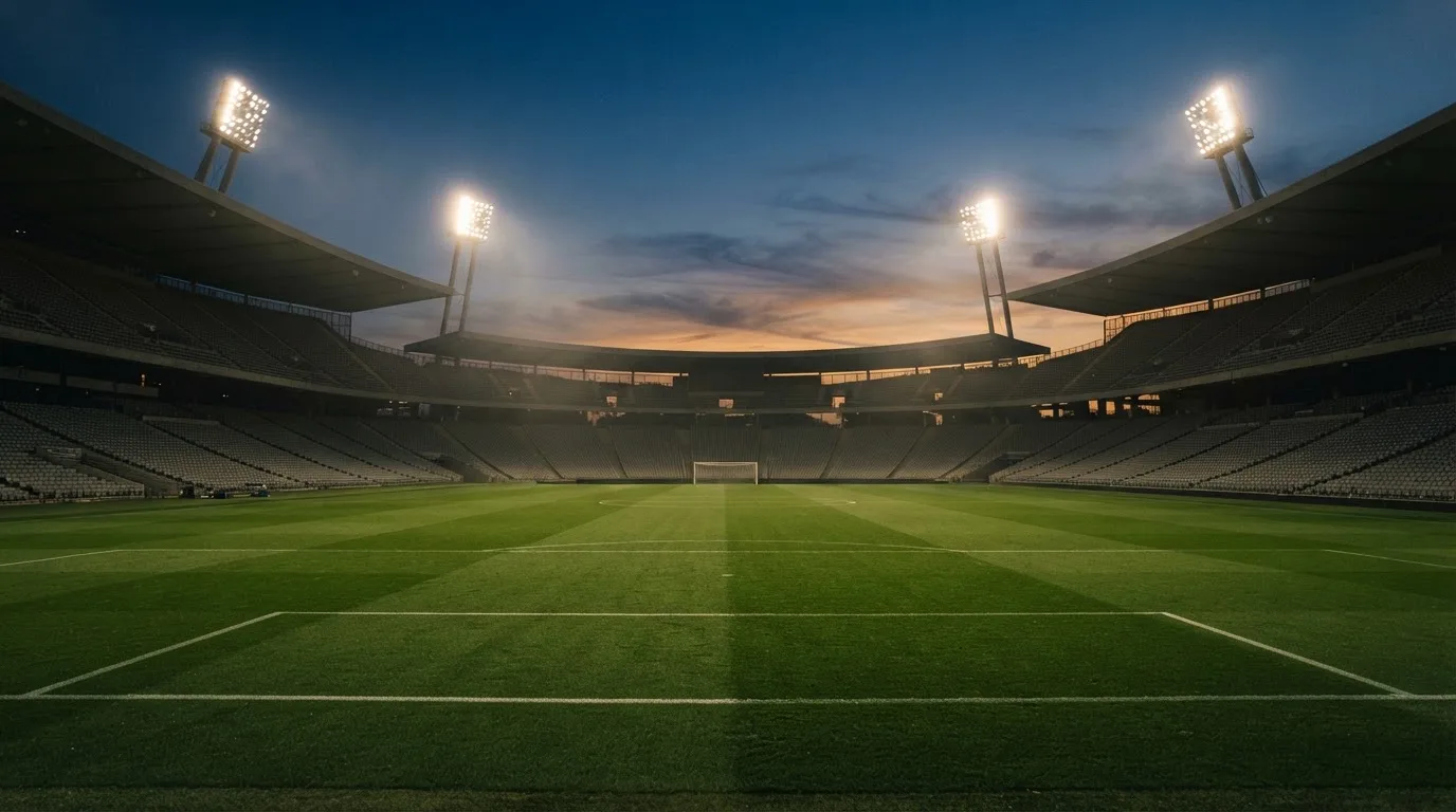 Een leeg voetbalstadion met lichtmasten bij schemering