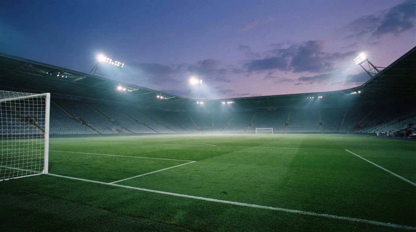 Een leeg voetbalstadion met lichtmasten bij schemering
