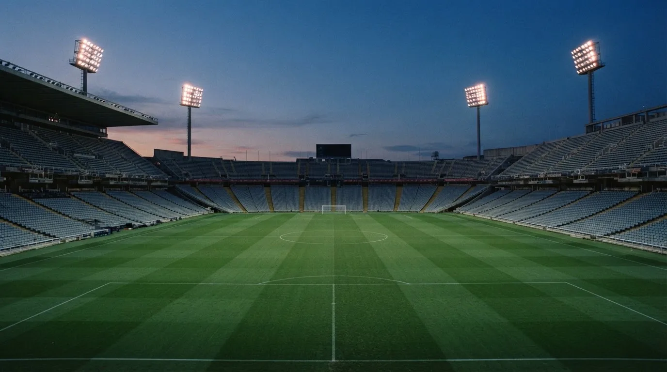 Een leeg voetbalstadion met lichtmasten bij schemering