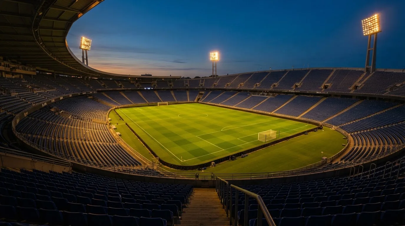 Een leeg voetbalstadion met lichtmasten bij schemering