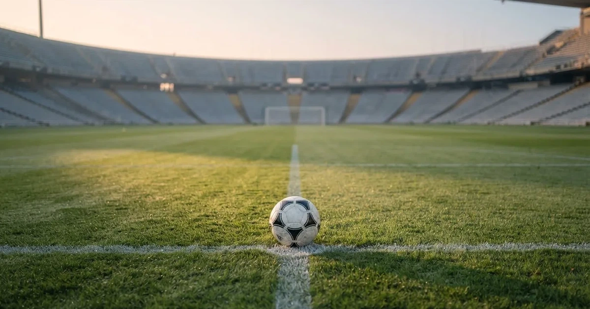 Een voetbal op de middenstip van een grasveld in het ochtendlicht