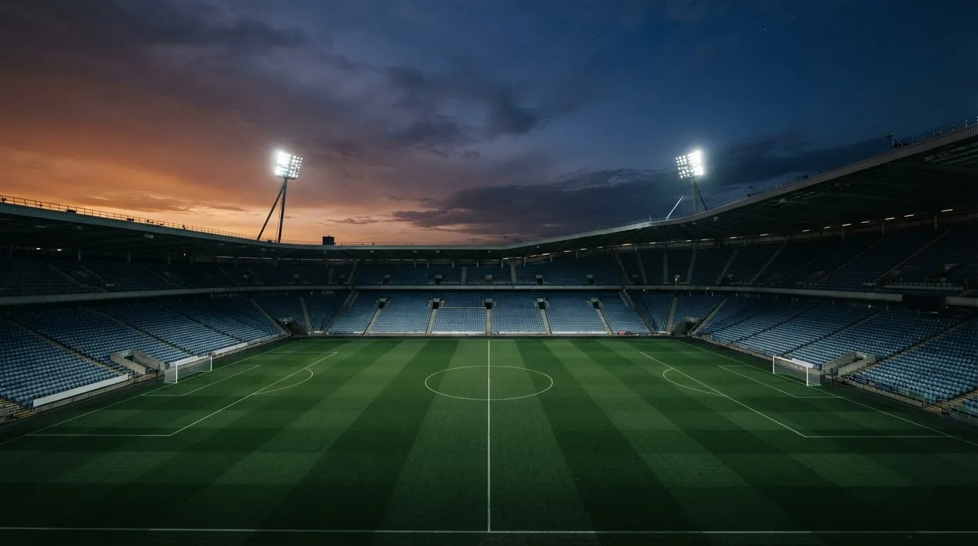 Een leeg voetbalstadion met lichtmasten bij schemering