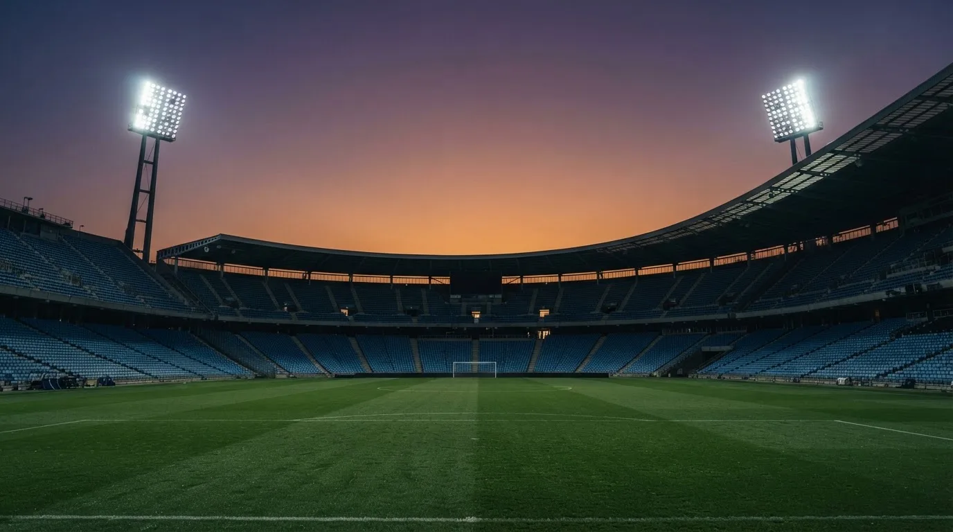 Een leeg voetbalstadion met lichtmasten bij schemering