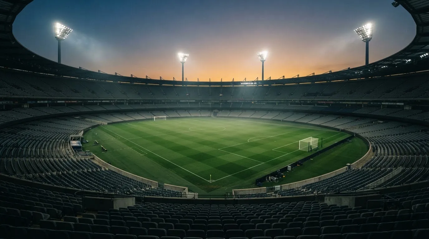 Een leeg voetbalstadion met lichtmasten bij schemering