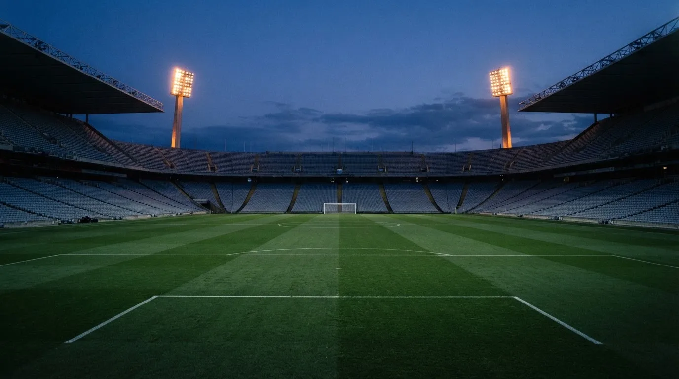 Een leeg voetbalstadion met lichtmasten bij schemering