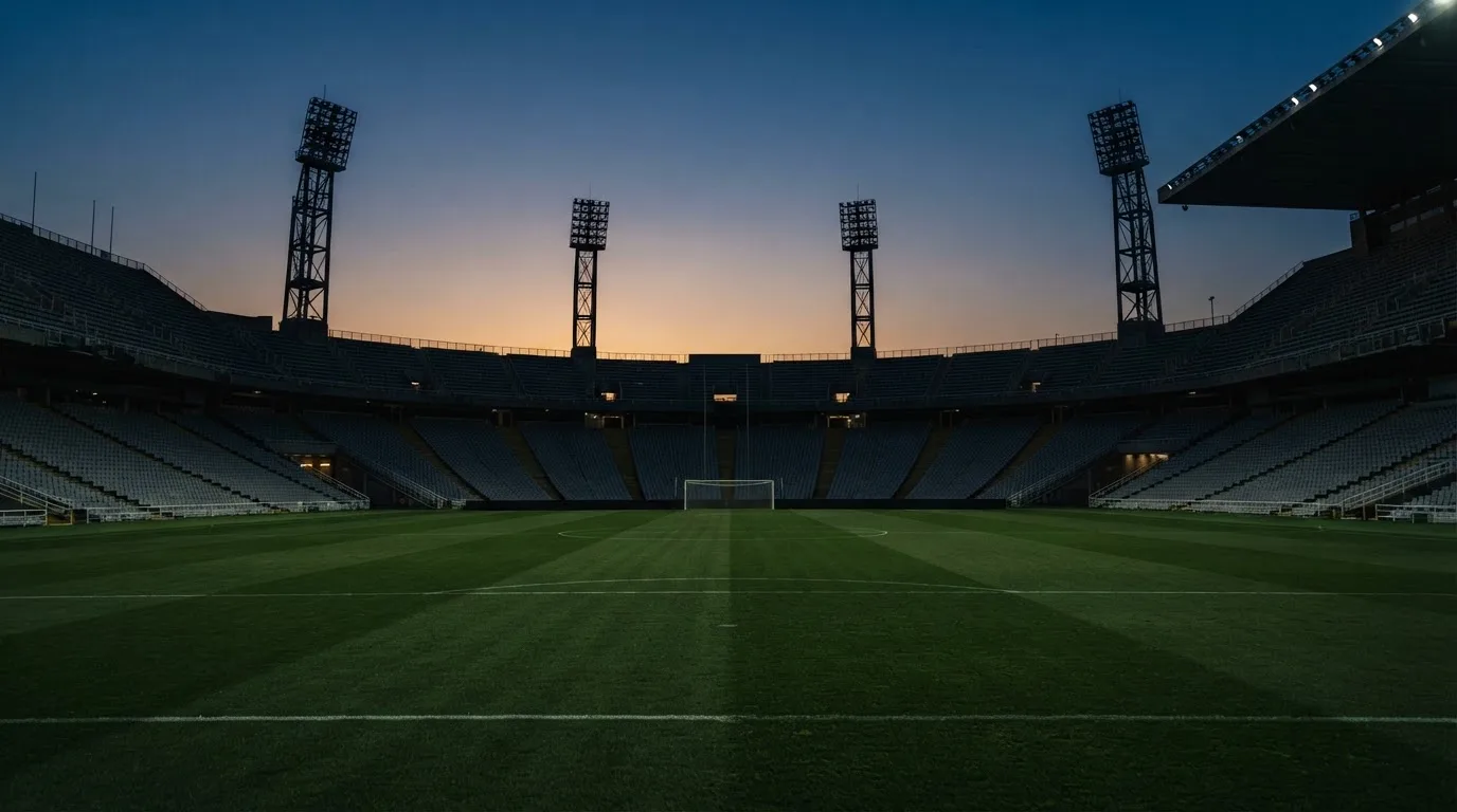 Een leeg voetbalstadion met lichtmasten bij schemering